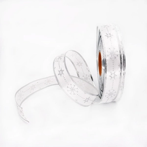 Close-up of white Christmas ribbon with silver glitter snowflakes and metallic edges