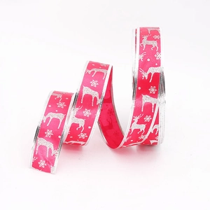 Macro detail of red Christmas ribbon featuring silver glitter reindeer and snowflake patterns