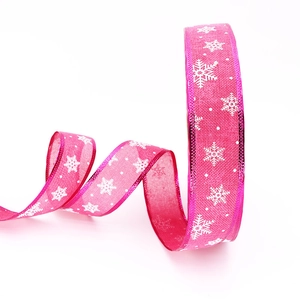 Detail of pink Christmas ribbon with white snowflake print and metallic edge trim