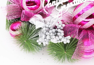 Detail of pink Christmas wreath with pine needles, glittery balls and silver Merry Christmas sign