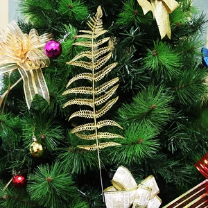 Glittering gold Christmas fern leaf decoration on a festive tree for holiday decor