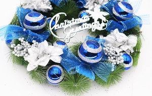 Detail of blue and silver Christmas wreath with pine needles and Christmas Greetings sign