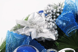 Detail of blue mesh ribbon and silver glitter flower on 40cm pine needle wreath