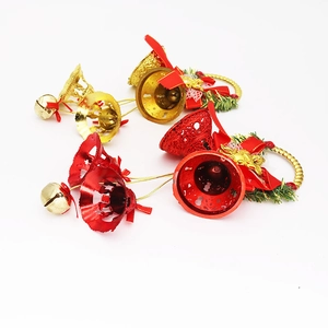 Macro detail of red and gold Christmas bell ornaments with silk bows and pine needles