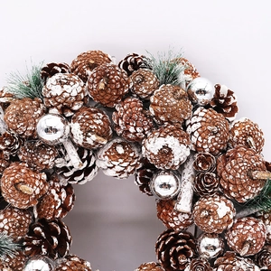 Detailaufnahme von Tannenzapfen mit Schneeeffekt und silbernen Ornamenten am Weihnachtskranz