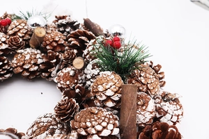 Close-up of white pine cone Christmas wreath with red berries and cinnamon sticks