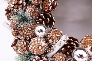 Detail eines Weihnachtskranzes mit verschneiten Zapfen, silbernen Kugeln und Nadeln