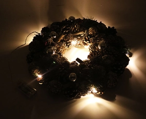 Detail of LED pine cone wreath showing warm lighting effect and festive silver ornaments