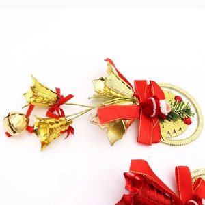 Detail of red bow, golden bells, and Santa doll on a festive Christmas tree wreath