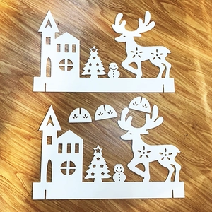 Flat lay of laser-cut white Christmas decor set with trees, reindeer and church scenes