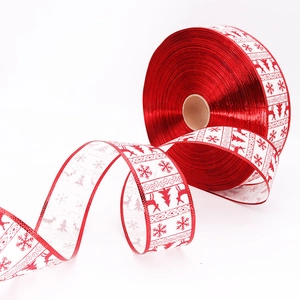 Detail of 5cm Christmas linen ribbon with red reindeer and snowflake patterns on a roll