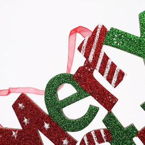 Macro view of Christmas hanging sign showing red glitter texture and green festive accents