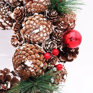 Détail macro de couronne de Noël avec pommes de pin enneigées et baies rouges sur blanc