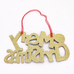 Detail of glittery gold Merry Christmas hanging sign with a festive red ribbon tie