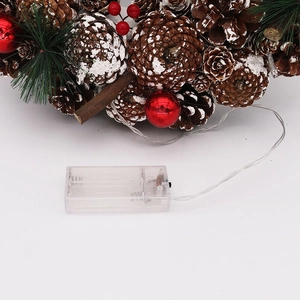 Détail de couronne de Noël avec pommes de pin, baies rouges et boîtier LED