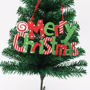 Close-up of glittery Merry Christmas hanging plaque with red ribbon on small tree