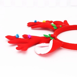 Detail of red plush Christmas reindeer headband with small bells and festive green leaf accents