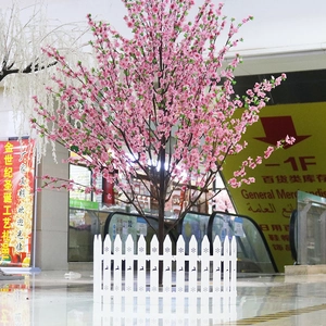 Close-up of artificial cherry blossom tree with white plastic picket fence decorations