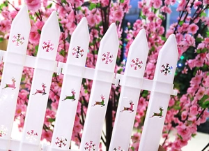 Close-up of white plastic holiday fence featuring hollow deer and snowflake patterns