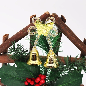 Festive Christmas bell ornament with golden bells, pine needles, and red berries on a white background