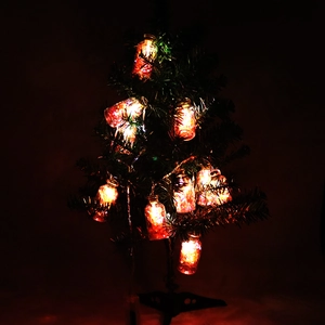 Close-up of LED glass bottle string lights on a mini Christmas tree with warm red glow
