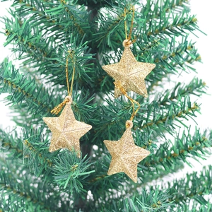 Macro detail of glittery gold star ornaments hanging on a green Christmas tree branch