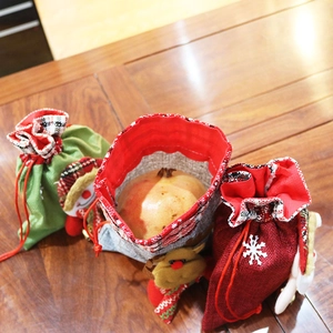 Three Christmas burlap gift bags with 3D reindeer and snowman on a dark wooden table