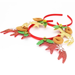 Detailansicht glitzernder Rentiergeweihe mit Glöckchen und Stechpalmen auf Weihnachtsstirnbändern