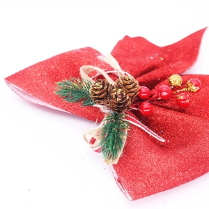 Détail d'un grand nœud de Noël rouge à paillettes avec pommes de pin et baies