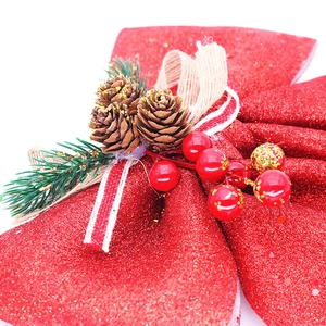 Gros plan de grand nœud de Noël rouge avec pommes de pin, baies et paillettes