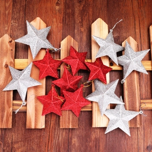 Detail of red and silver glitter star ornaments hanging on a rustic wooden fence