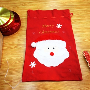 Close-up of red velvet Christmas gift bag with Santa Claus applique and drawstring