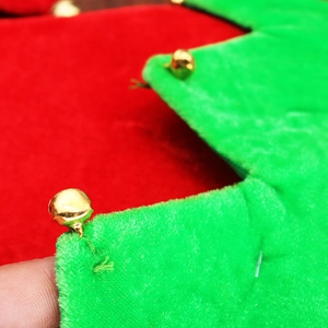Macro view of Christmas elf hat featuring red and green velvet fabric with gold jingle bells