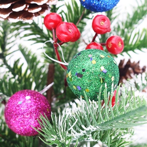 Macro detail of glitter Christmas balls, red berries, and pine cones on white background
