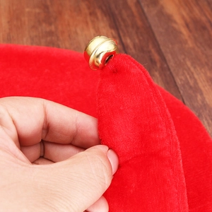 Red felt Christmas elf hat with golden bell detail on a wooden background