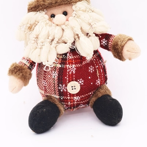 Dettaglio di Babbo Natale di peluche con abito a quadri rossi e barba di lana bianca
