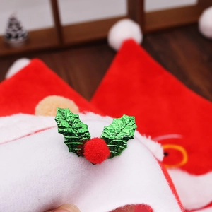 Dettaglio cappello di Natale in velluto rosso con bordo in peluche e decoro di agrifoglio