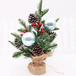 Close-up of mini Christmas tree with blue ornaments, pine cones, and burlap base