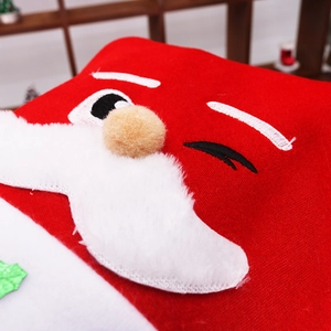 Dettaglio del ricamo di Babbo Natale con barba di peluche su tessuto rosso festa