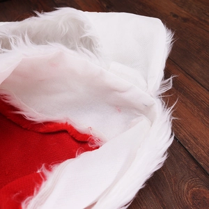 Bonnet de Noël rouge classique avec bordure en peluche blanche sur fond de bois