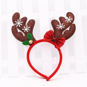 Christmas reindeer antler headband with festive bow and holly bell on white fence