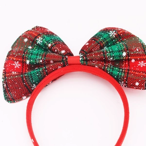 Detail of red and green plaid Christmas headband with a large snowflake bow