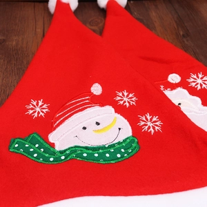 Detailed embroidery of a smiling snowman on a red felt Christmas hat with white snowflake motifs