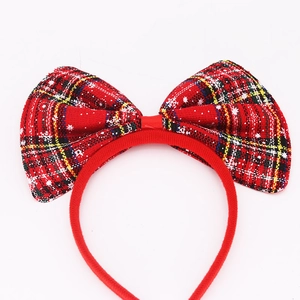 Detail of red plaid Christmas bow headband with white snowflake patterns on red velvet band