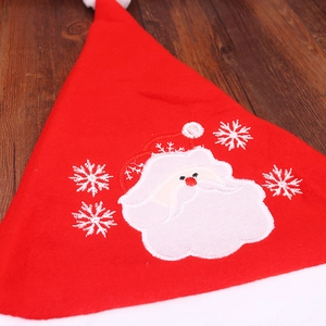Close-up of embroidery details on a red Christmas hat with Santa Claus and snowflake patterns