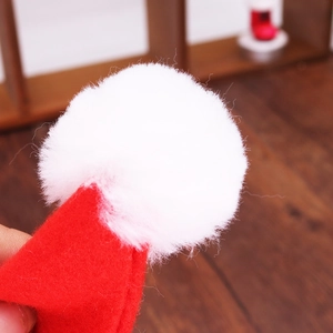 Close-up of mini red felt Christmas hat with fluffy white pom-pom for bottle decoration