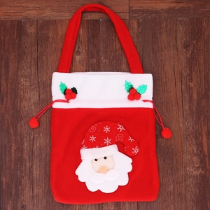 Detail of red Christmas gift bag featuring 3D Santa Claus and furry drawstring balls