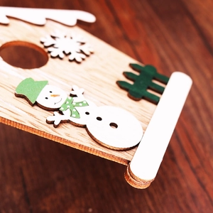 Detailansicht eines hölzernen Weihnachtsanhängers mit bemaltem Schneemann und Schneeflocke