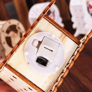 Detailed close-up of wooden Christmas house base with power switch and battery compartment