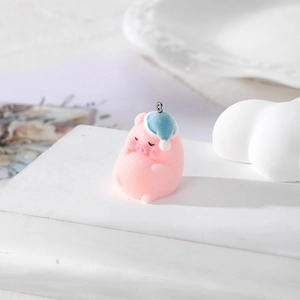 Detail of pink flocked pig pendant with blue sleeping cap on a white display stand